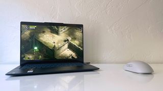 The Lenovo Yoga Slim 7x running Death's Door on a white desk next to a gray gaming mouse